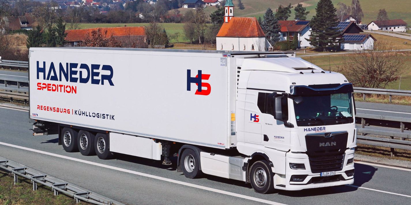 HANEDER MAN TGX mit Kühlauflieger auf der Landstraße vor einem bayerischen Dorf